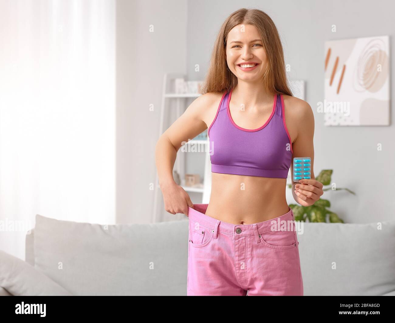 Mujer con ropa suelta y con pastillas para bajar de peso en casa Fotografía  de stock - Alamy