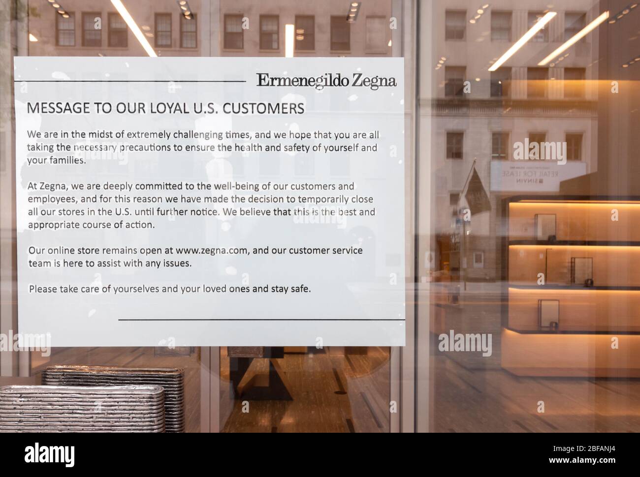 Letrero cerrado temporalmente en la tienda Ermenegildo Zegna en w 57th St., debido al coronavirus o a la pandemia de covid-19, en el fondo están los estantes vacíos Foto de stock