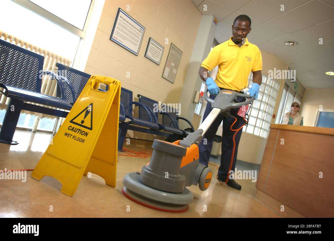 Un empleado de Rentokill Initial Hospital Services puliendo el piso de la sala de espera. Foto de stock