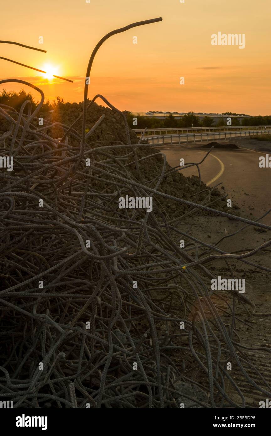 Acero estructural Residuos de la demolición de un puente al atardecer en un sitio de construcción de puentes y construcción de carreteras, silueta con sol Foto de stock