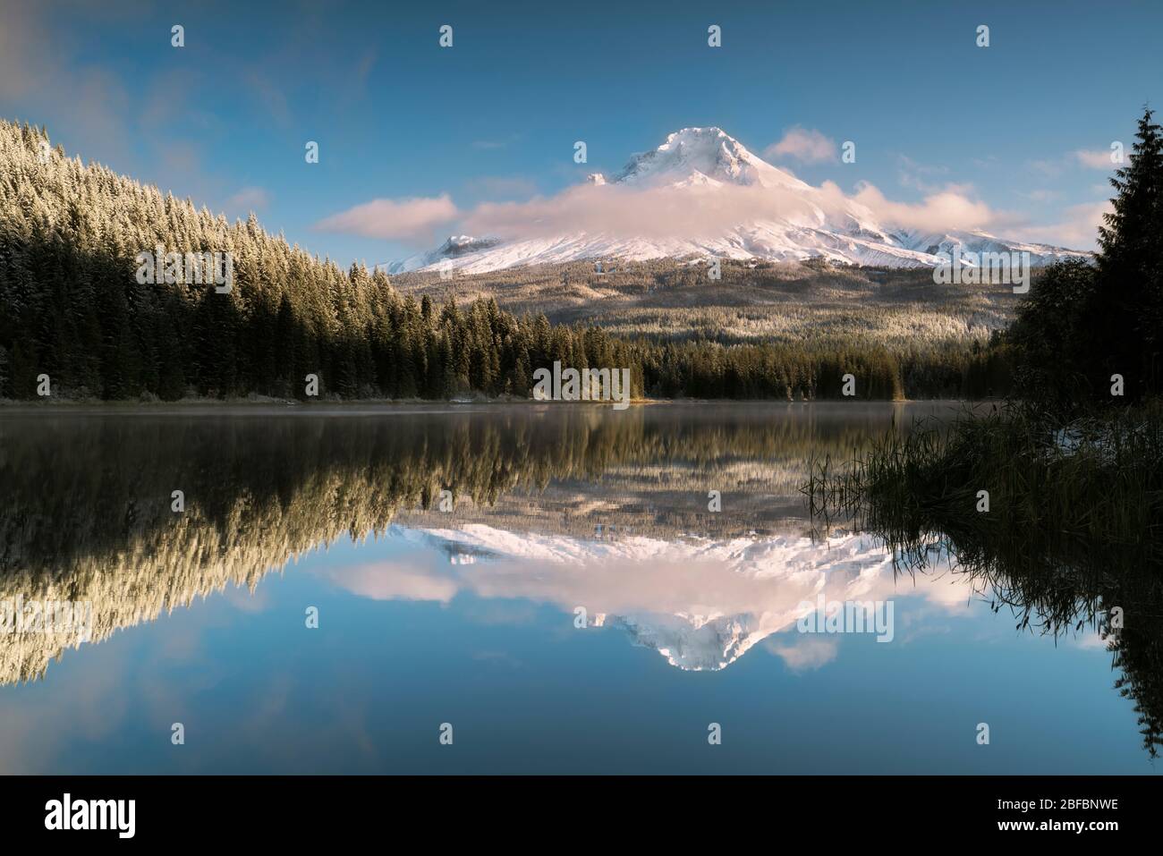 Las nubes de la mañana temprano se forman en parte para revelar la fresca Nevada otoñal en el pico más alto de Oregón, el Monte Hood que se refleja en el Lago Trillium. Foto de stock