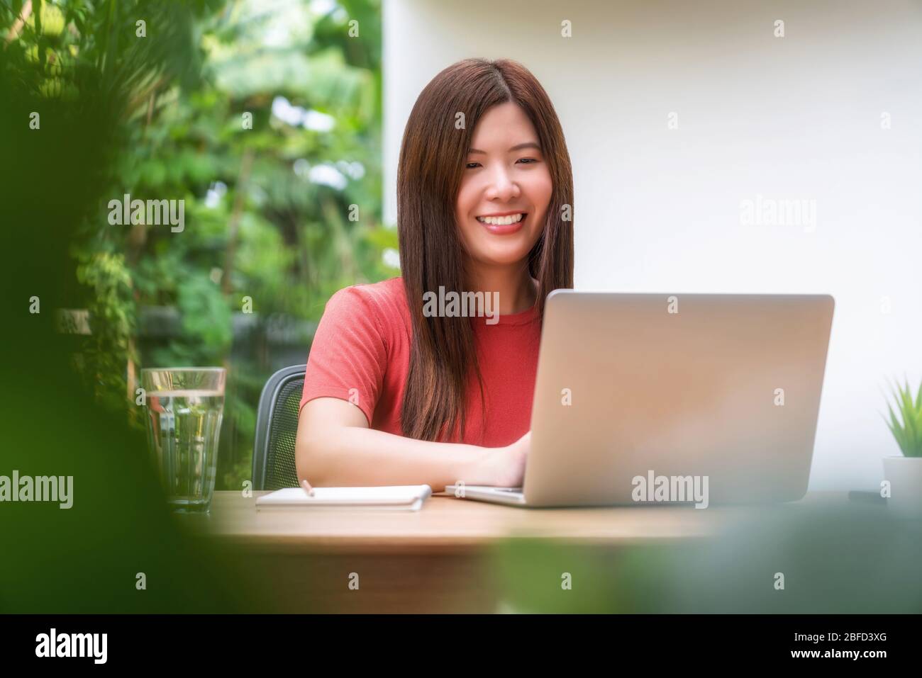 Mujer asiática de negocios que utiliza la tecnología portátil para trabajar desde casa en el hogar y jardín al aire libre, startups y propietario de negocios, covid19 social distancia an Foto de stock