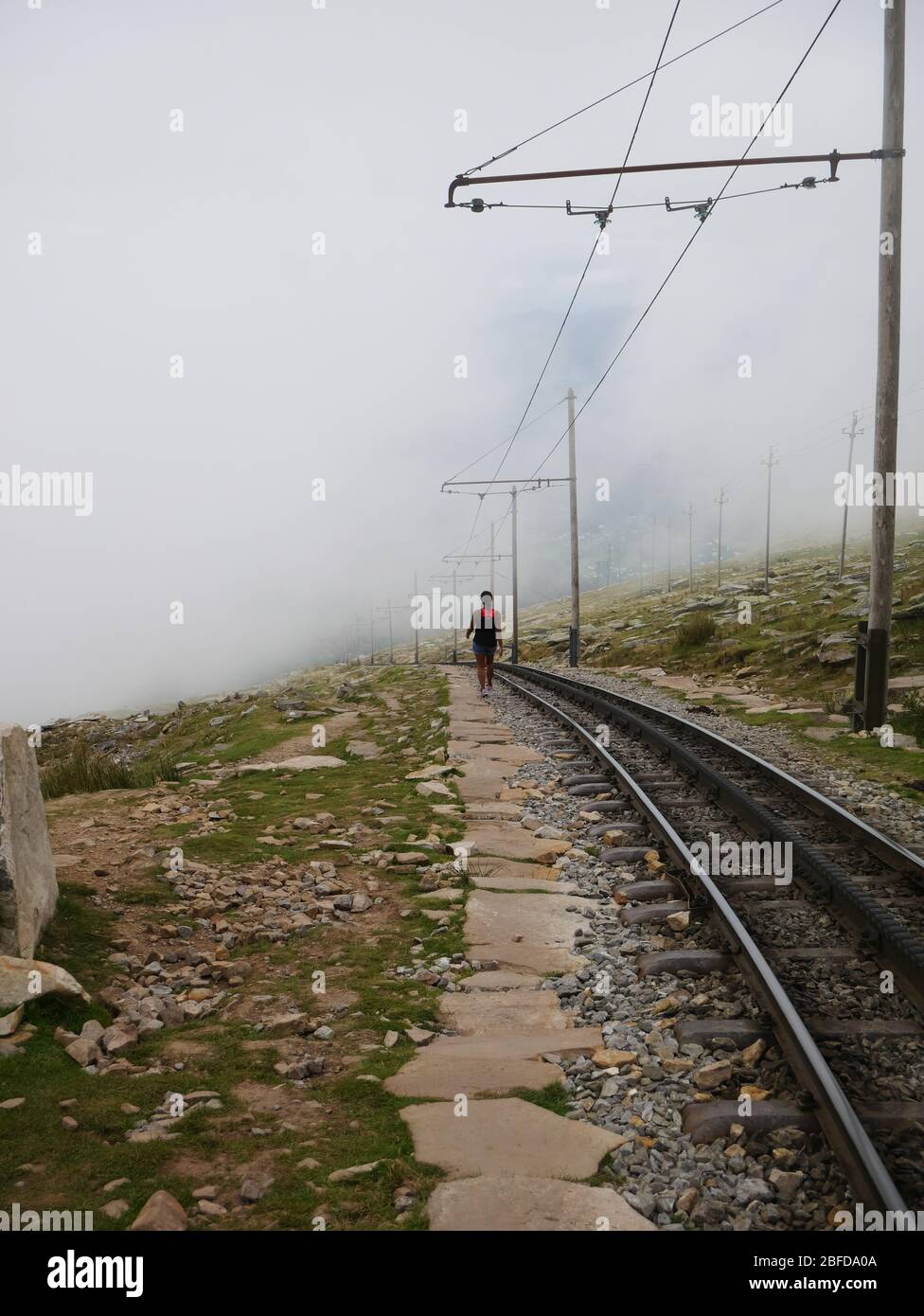 Silueta de una mujer solitaria que se va a la distancia, hacia un paisaje brumoso Foto de stock
