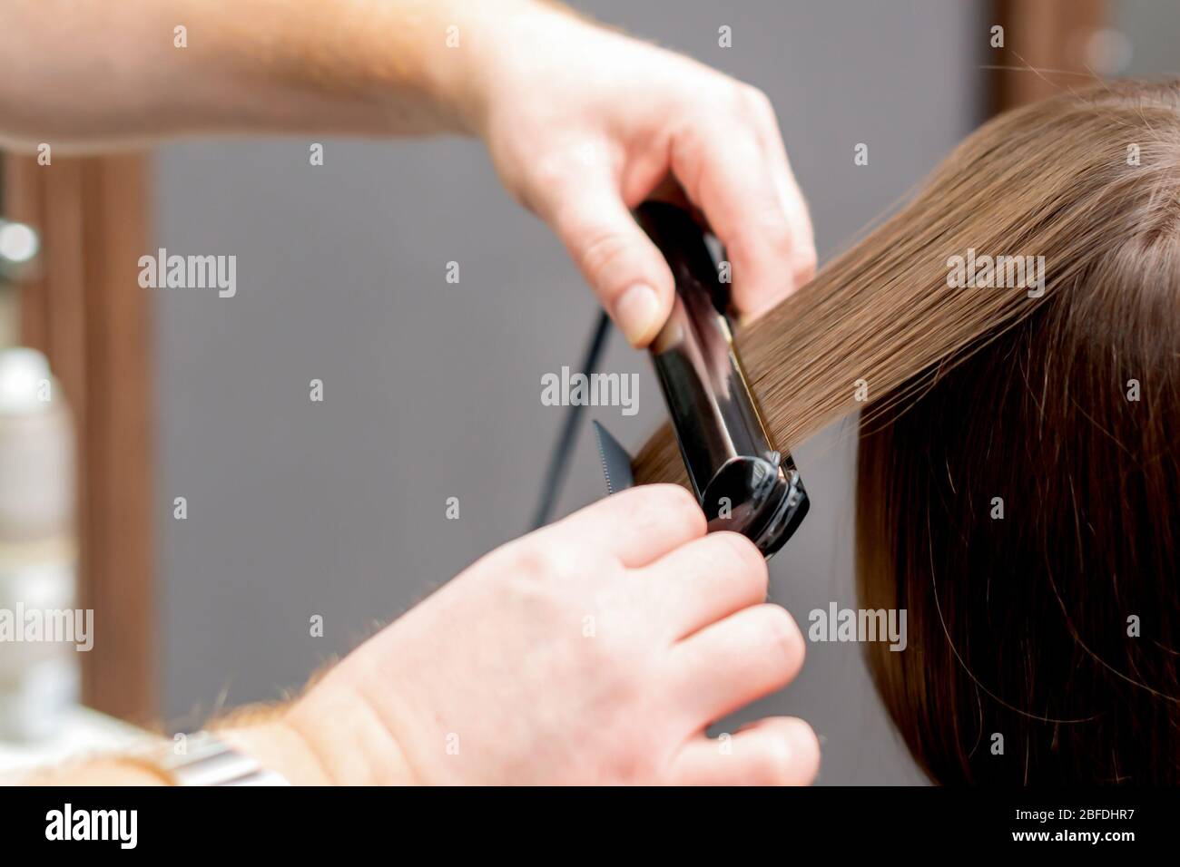 Las manos de peluquería son el alisado del pelo de la mujer con la  herramienta para alisar en la peluquería, vista posterior Fotografía de  stock - Alamy