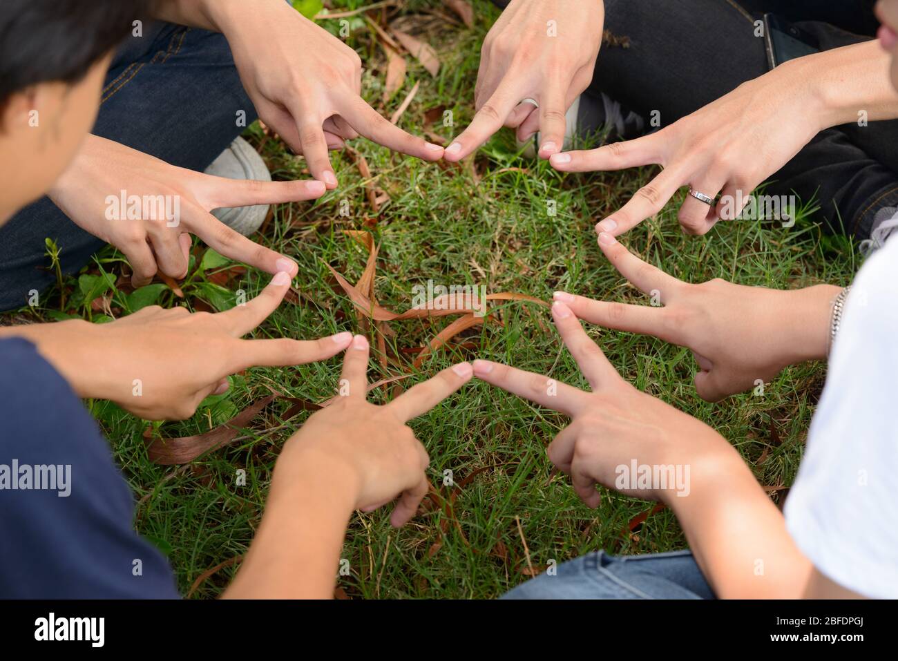 Grupo de amigos formando los dedos como estrella juntos como concepto de trabajo en equipo Foto de stock