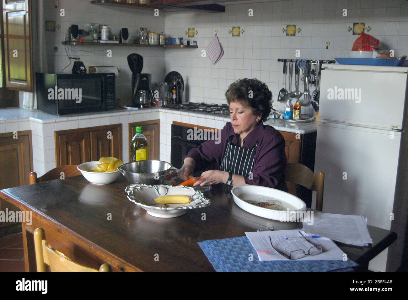 Una mujer americana de mediana edad que prepara el almuerzo en una villa alquilada en Torrita di Sienna, en la región toscana de Italia. Foto de stock