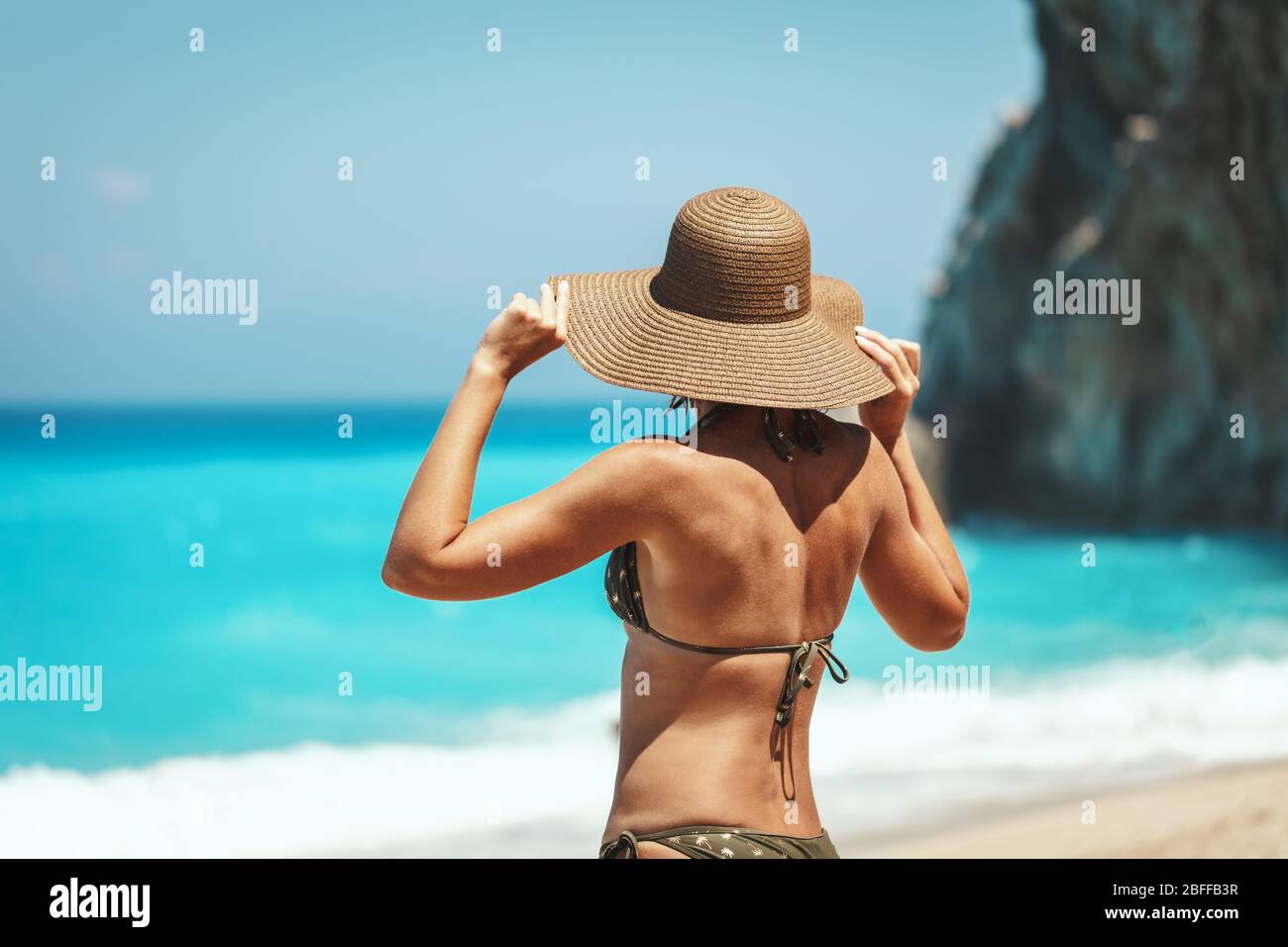 Mujer guapa de mediana edad en bikini con sombrero de paja y disfrutar de  tomar el sol en la playa junto al océano Fotografía de stock - Alamy