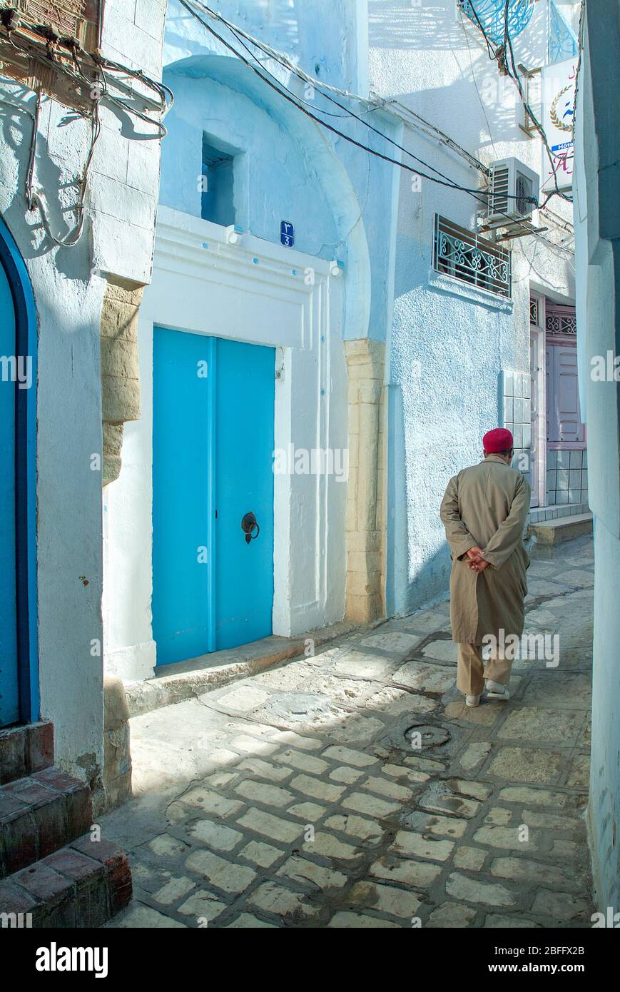 Hombre local con vestido tradicional caminando por calles estrechas, Medina, Sousse, Túnez Foto de stock