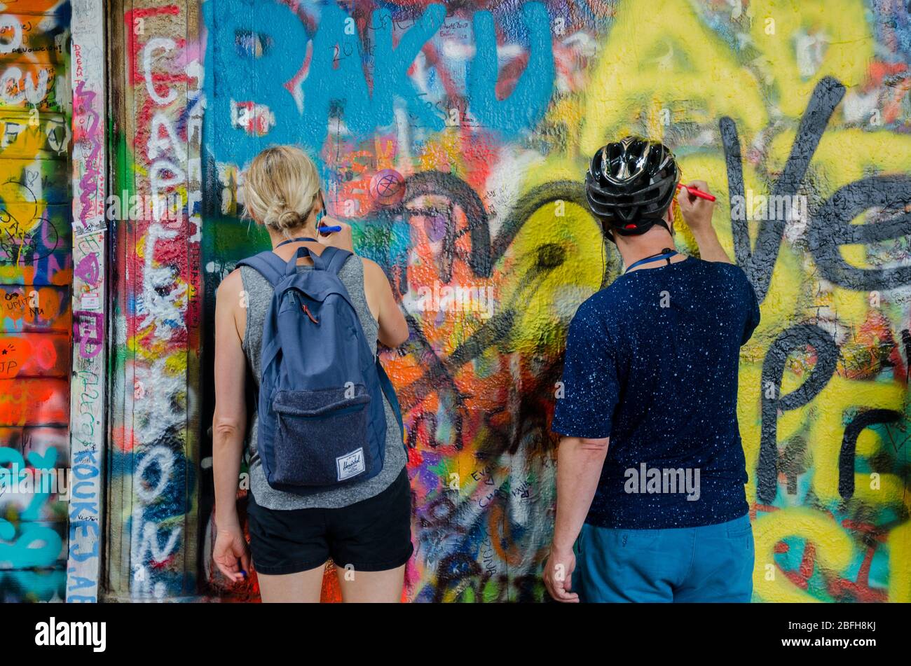 Una pareja escribe su corazón en el Muro de John Lennon en Praga, República Checa Foto de stock