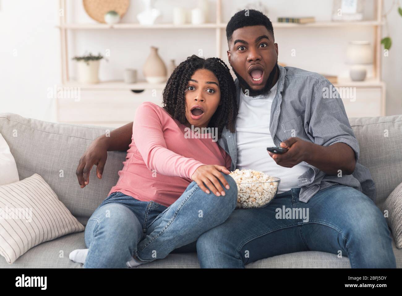 Una pareja de negros con zapatos mirando una película de miedo y comiendo  palomitas en casa Fotografía de stock - Alamy