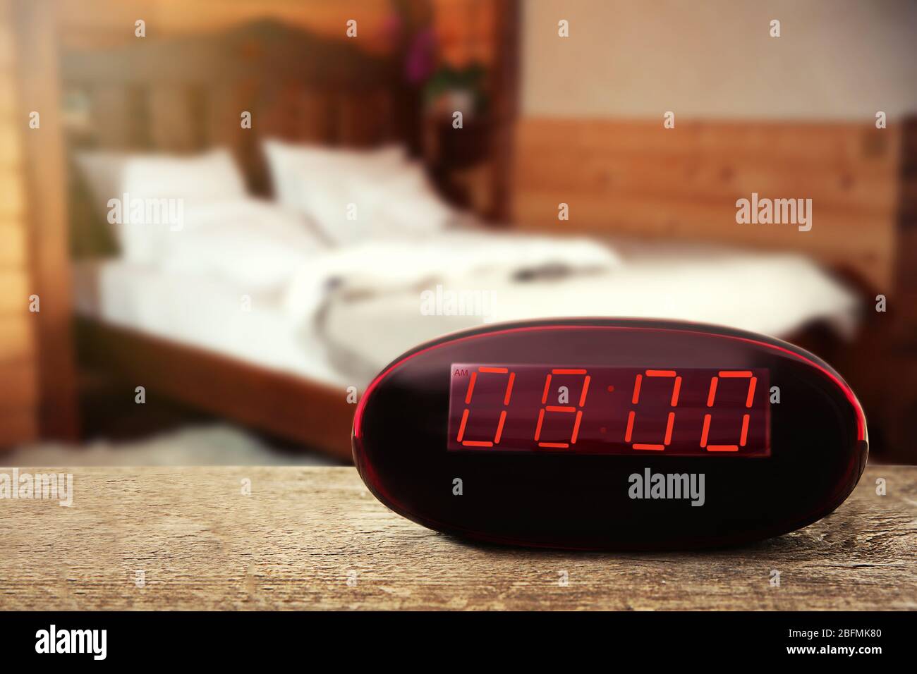 Reloj digital que muestra las 8:00 en punto sobre mesa de madera,  dormitorio de fondo Fotografía de stock - Alamy