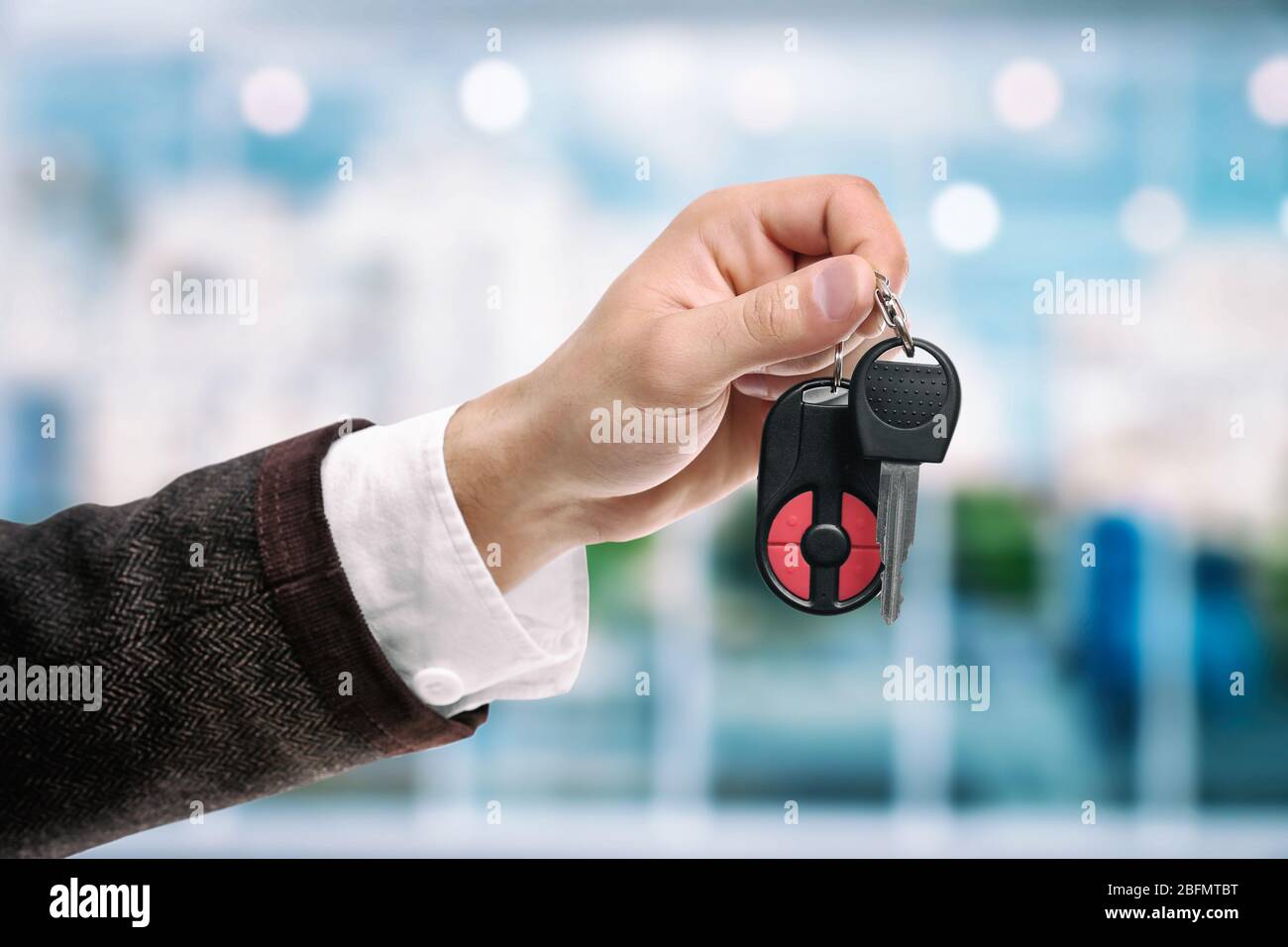 Hombre de negocios que mantiene la llave del coche sobre un fondo brillante Foto de stock