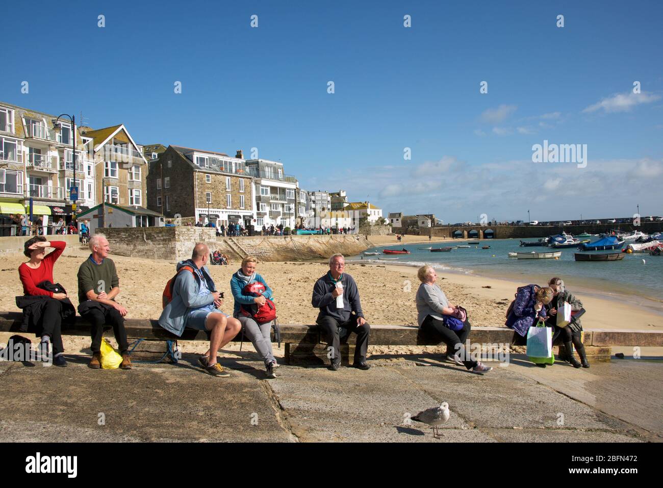 Línea de gente tomando sol en el día de otoño St Ives Cornwall England Foto de stock