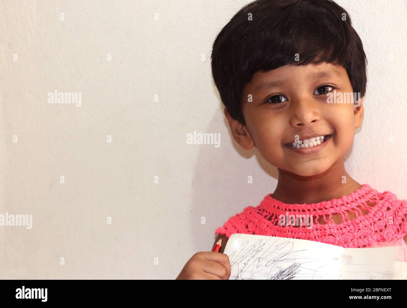 Una niña pequeña con cara sonriente y fondo blanco suave se ve muy hermoso Foto de stock