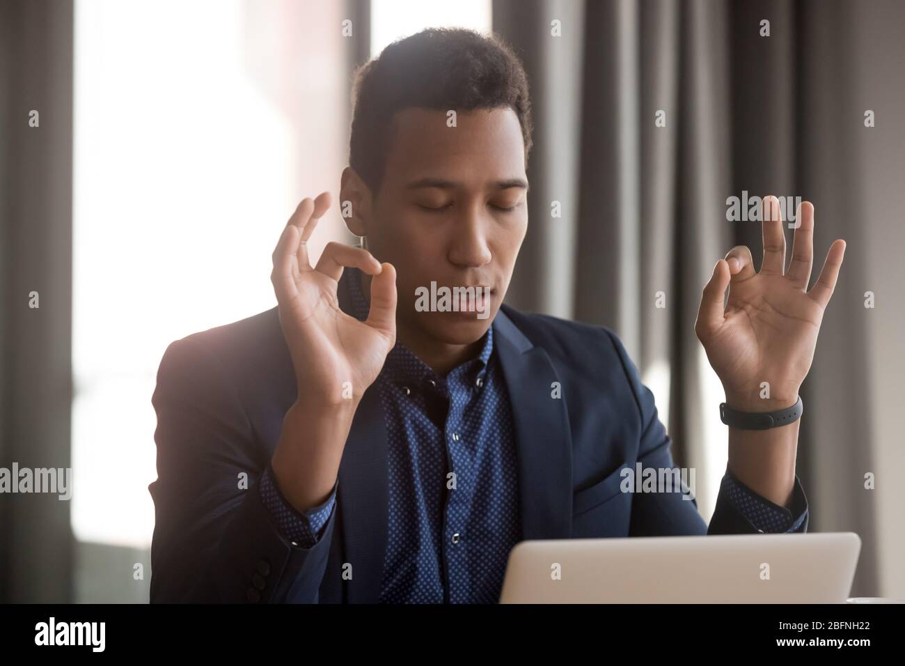 Un hombre de negocios africano cerrado los ojos los dedos doblados reducen las situaciones estresantes Foto de stock