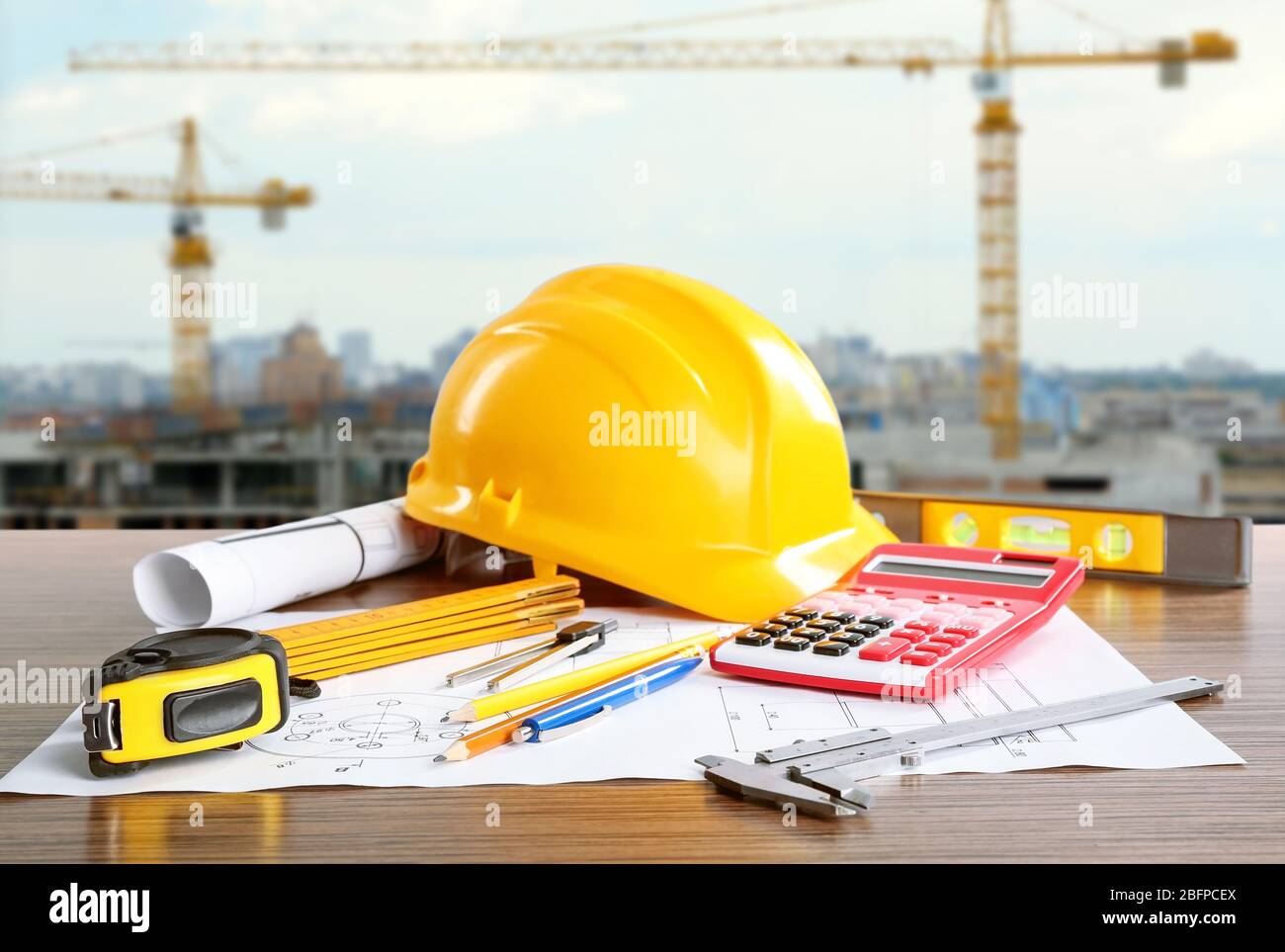 Planos de construcción con herramientas y casco sobre fondo de construcción Foto de stock