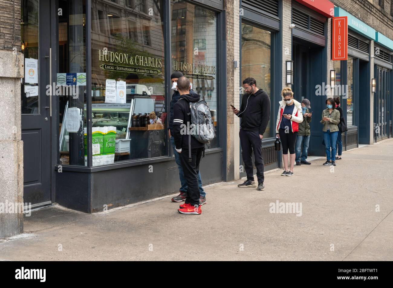 Nueva York, NY, EE.UU. 19 de abril de 2020. Personas que practican distanciamiento social como resultado del receso del Coronavirus mientras están en línea fuera de una carnicería Foto de stock