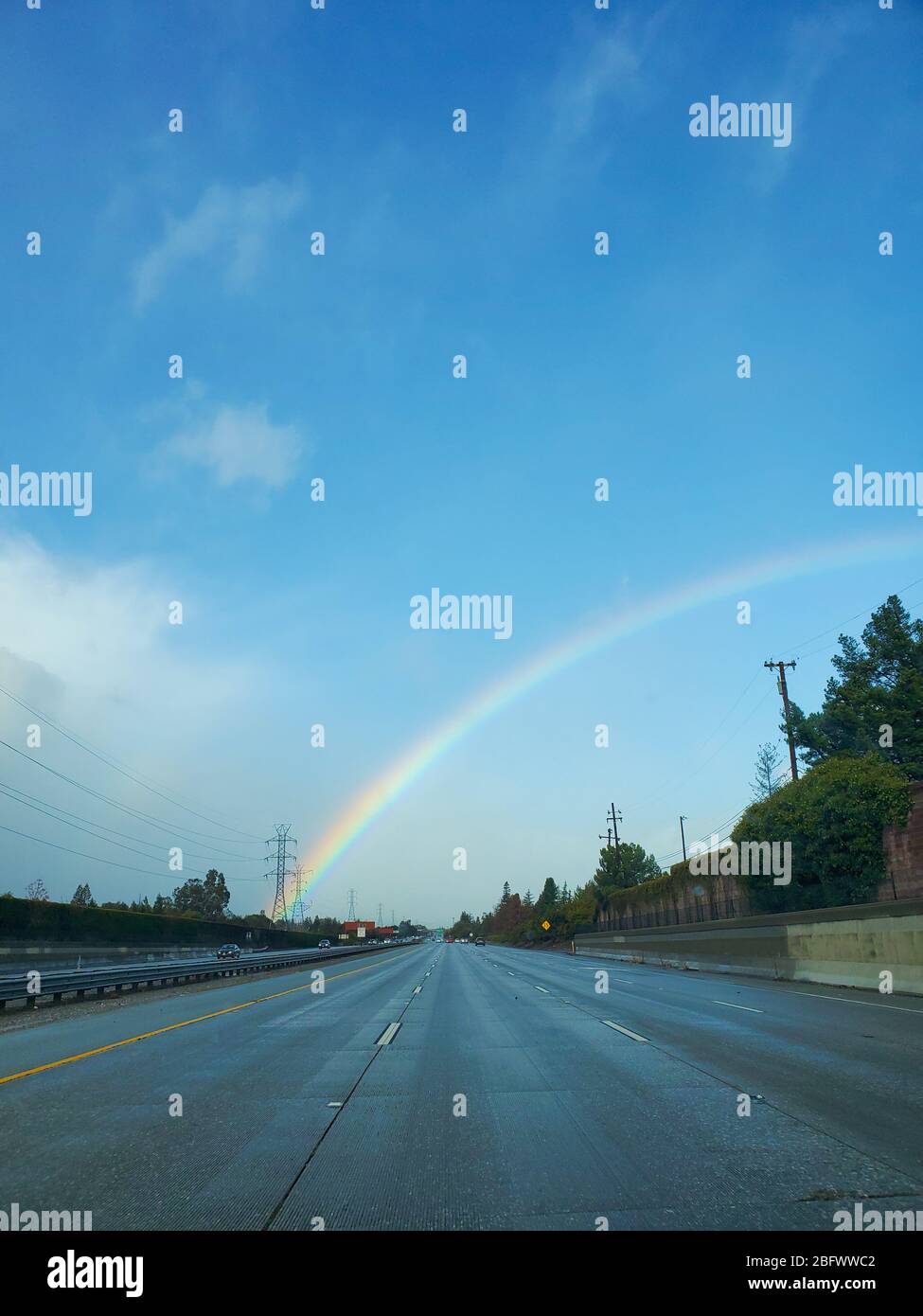 Un colorido arco iris sobre una autopista en un día soleado Foto de stock