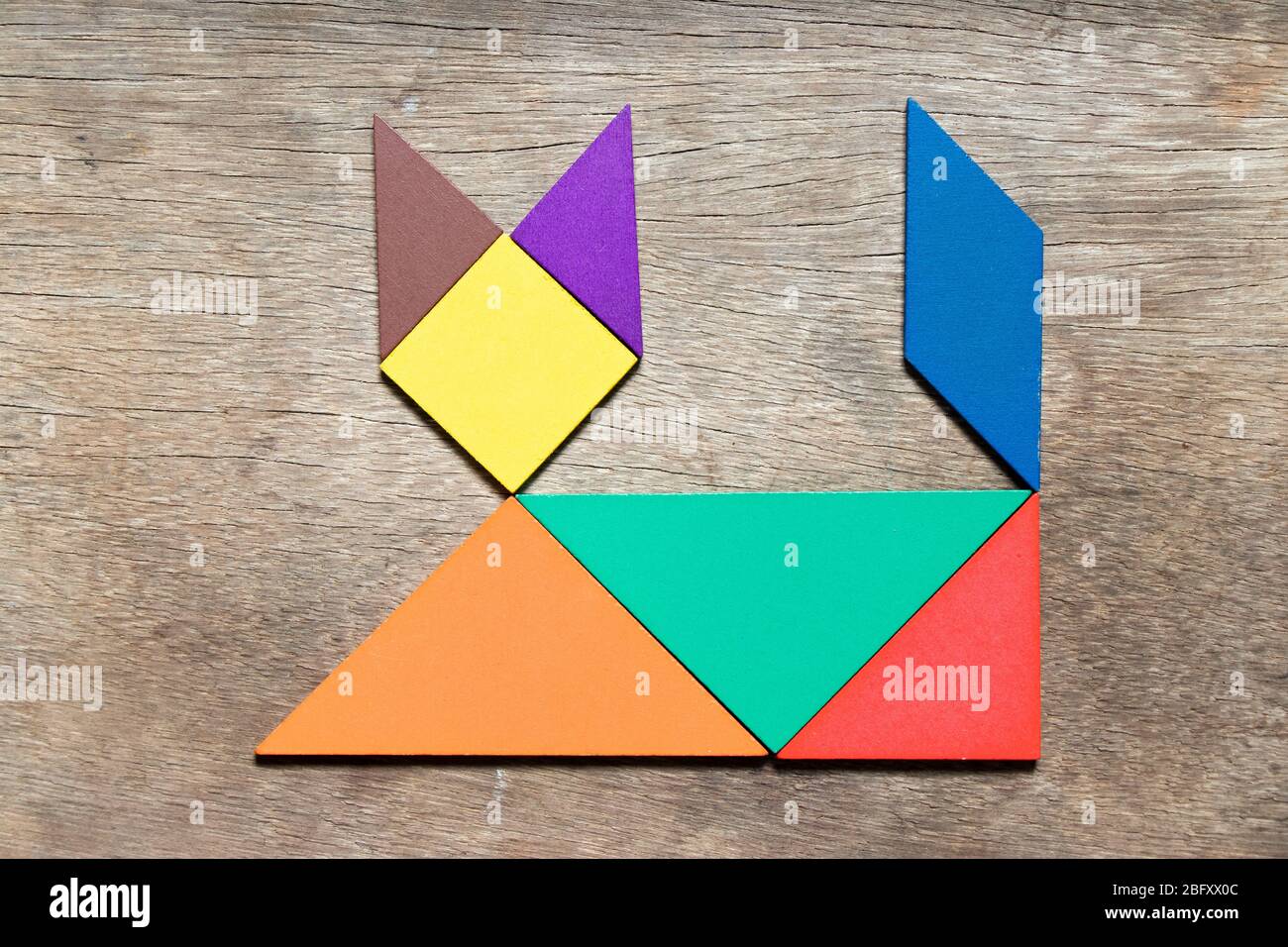 Suposiciones, suposiciones. Adivinar Varios Regularidad Tangram del color en forma del gato acostado sobre fondo de madera  Fotografía de stock - Alamy