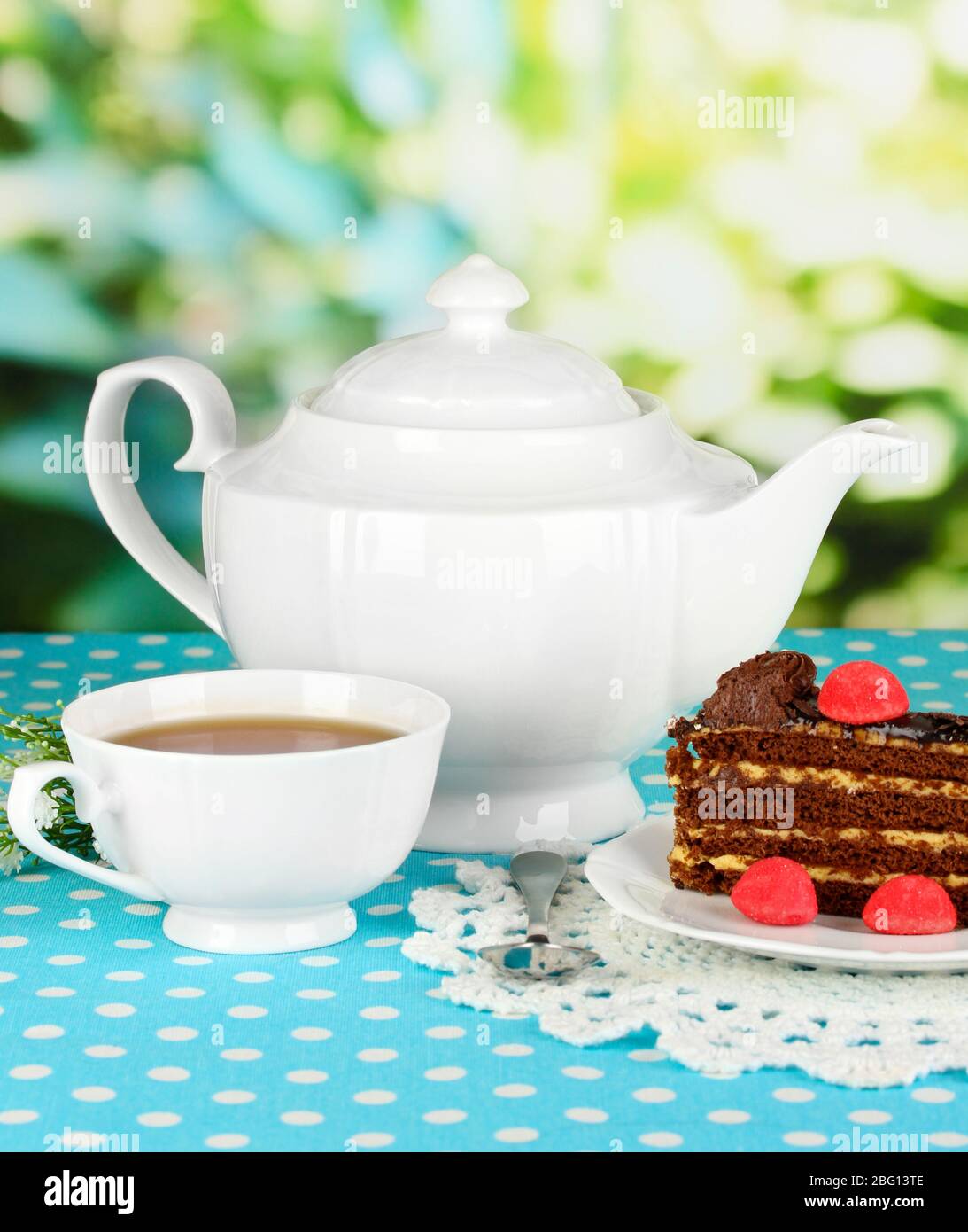Tetera, taza de té y deliciosa tarta sobre fondo natural Foto de stock