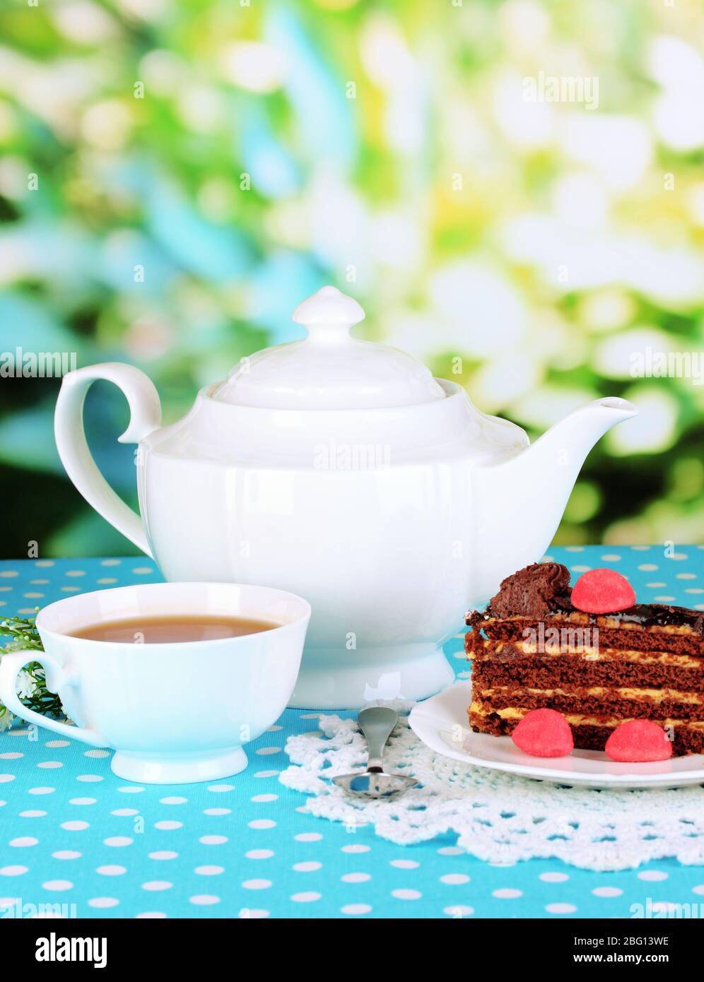 Tetera, taza de té y deliciosa tarta sobre fondo natural Foto de stock