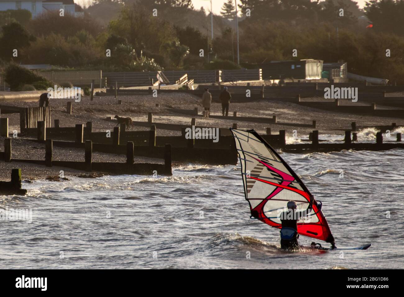 Un surfista se prepara para montar en su tabla de windsurf titchfield, Hampshire Foto de stock