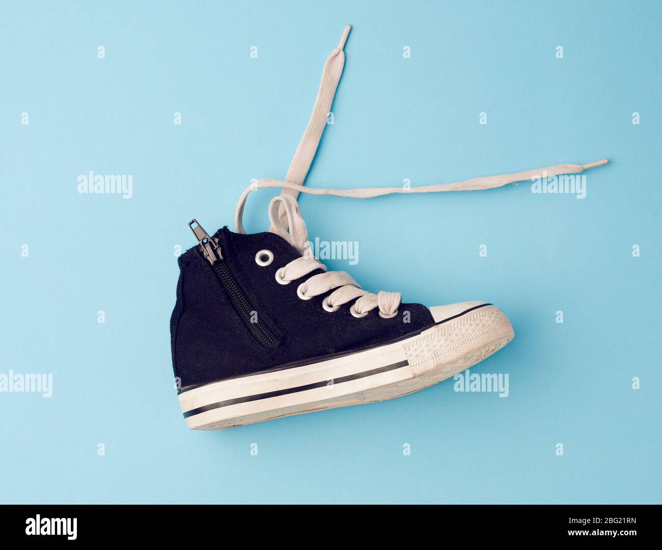 sneakers para niños de tela negra con cordones de calzado blanco sin atar  sobre un fondo blanco, los zapatos se paran lateralmente Fotografía de  stock - Alamy