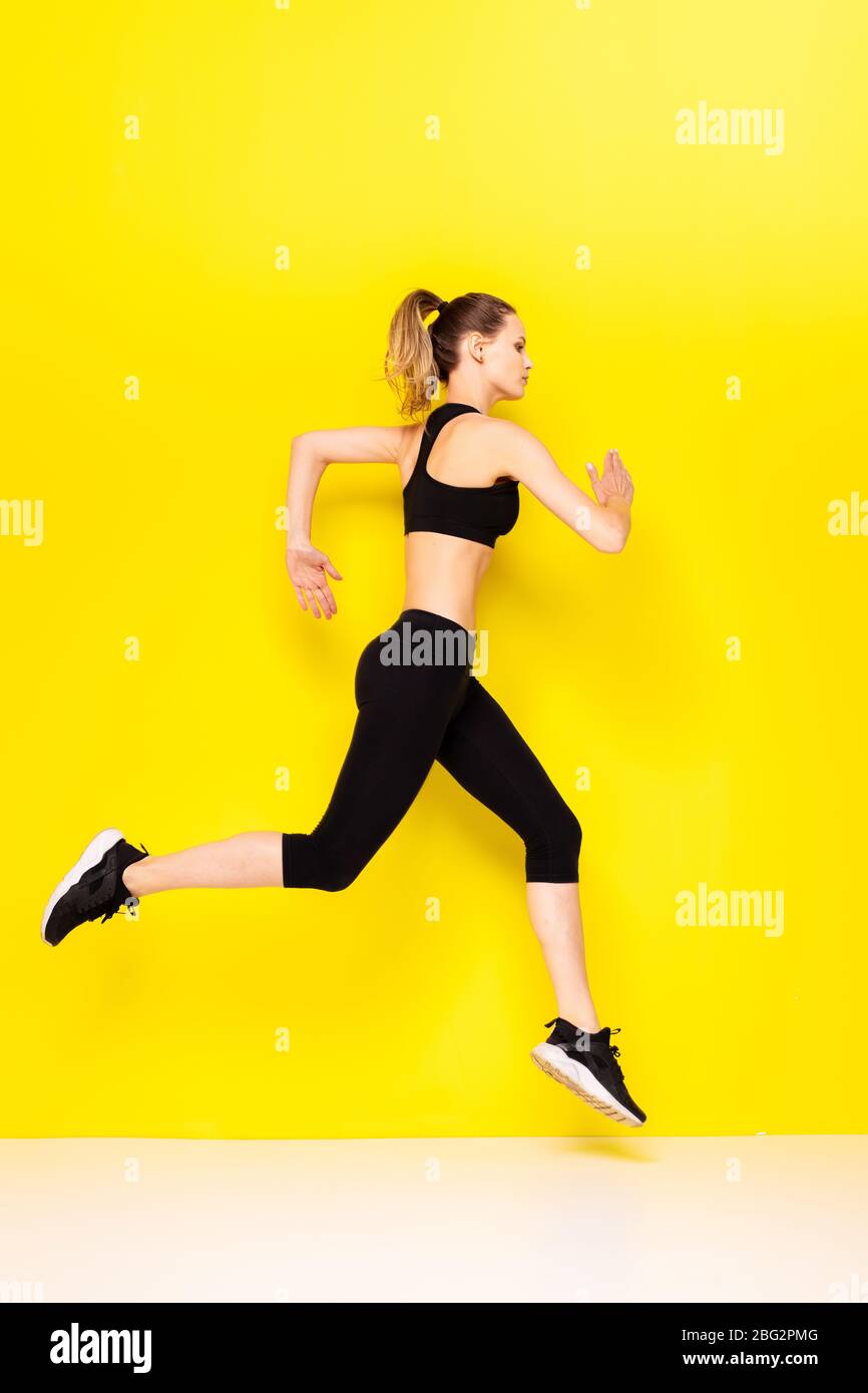 Mujer deportiva runner en silueta sobre fondo amarillo. Foto de mujer  atractiva en ropa de moda. Movimiento dinámico. Vista lateral. Deporte y él  Fotografía de stock - Alamy