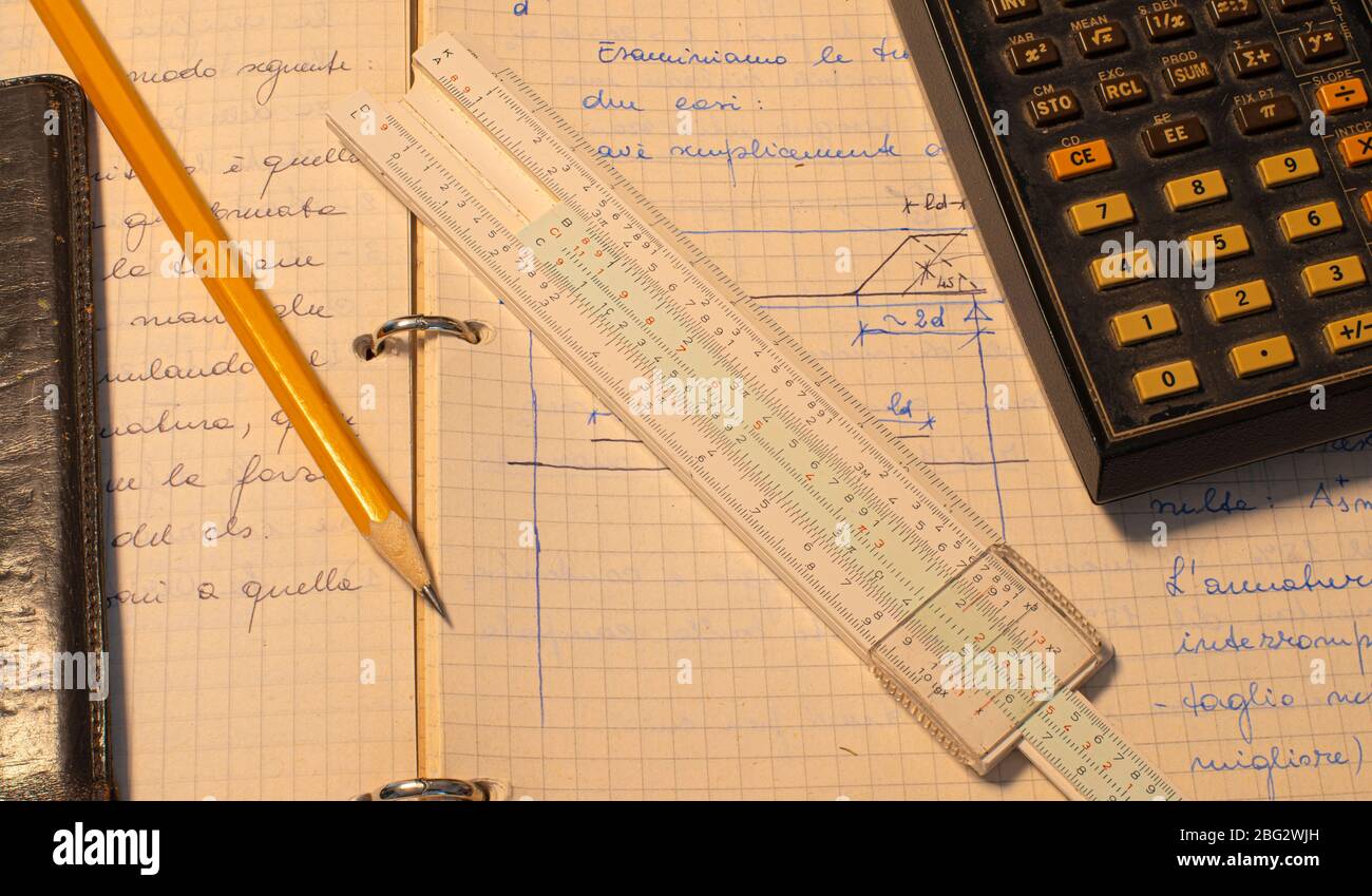 Lápiz, regla de diapositivas antigua y página de calculadora electrónica científica con los cálculos en curso Foto de stock