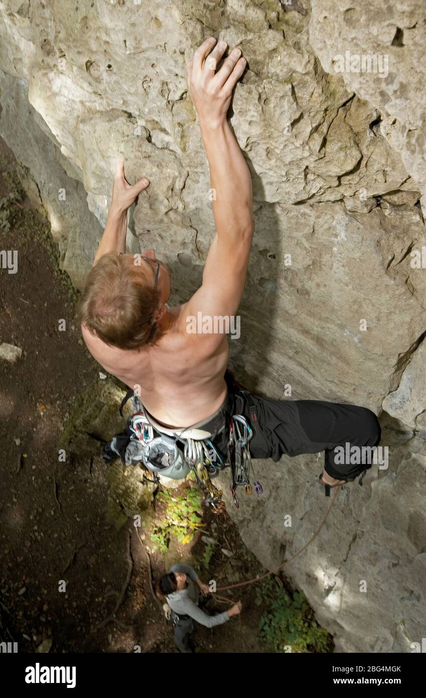 Joven hombre escalando acantilado de piedra caliza en el norte de Alemania Foto de stock