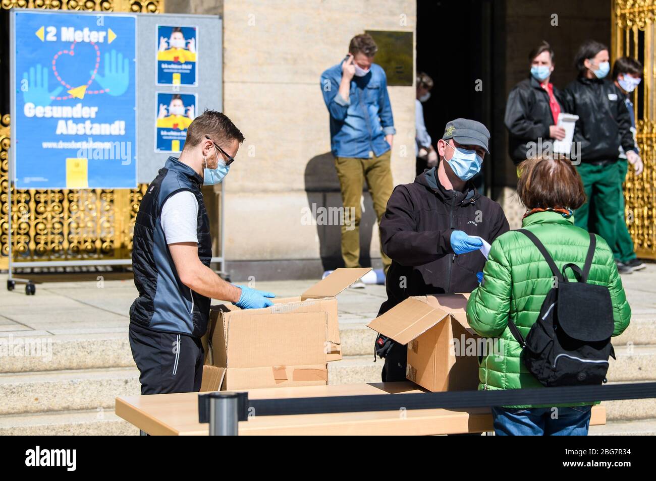 (200420) -- DRESDEN (ALEMANIA), 20 de abril de 2020 (Xinhua) -- un miembro del personal (R) ofrece una máscara facial a una mujer frente al Ayuntamiento de Dresden, estado de Sajonia, Alemania oriental, el 20 de abril de 2020. La tasa de nuevas infecciones con COVID-19 en Alemania continuó disminuyendo, ya que el número de casos confirmados sólo aumentó en 1,775 en un día a casi 142,000, anunció el lunes el Instituto Robert Koch (RKI). (Foto de Kevin Voigt/Xinhua) Foto de stock