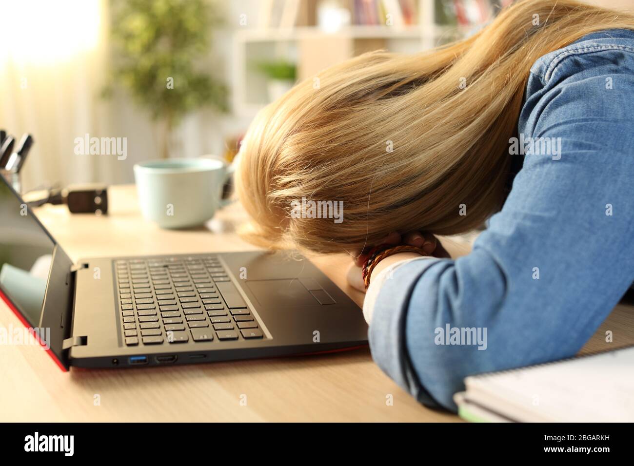 Cerca de una estudiante cansada y sobrecargada durmiendo sobre el escritorio durante el día en casa Foto de stock