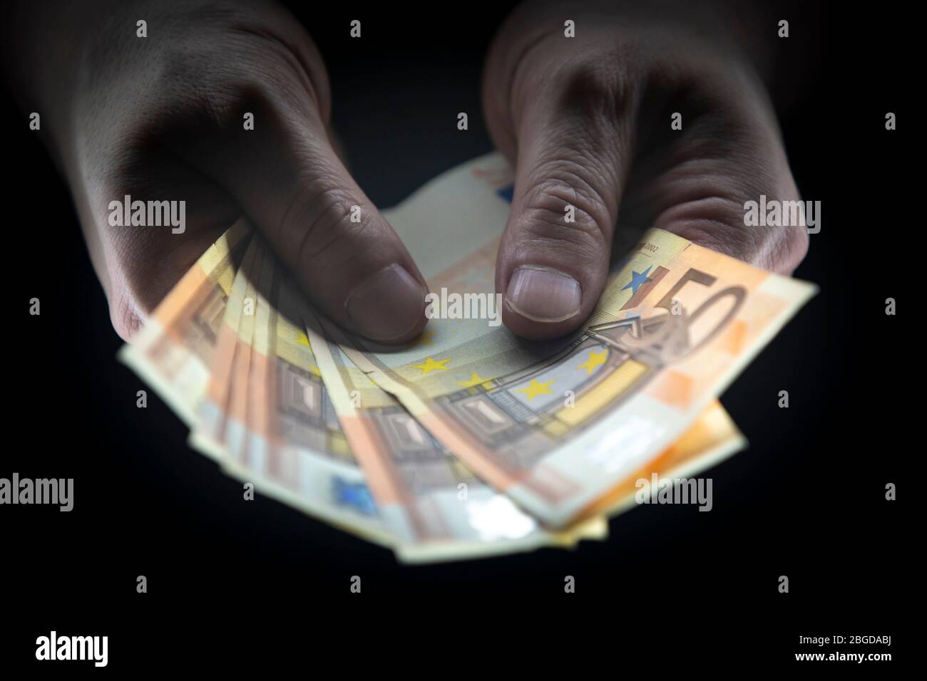 Hombre que sostiene 50 BILLETES DE EUROS en una habitación oscura, dinero ilegal, concepto de avaricia. Foto de stock