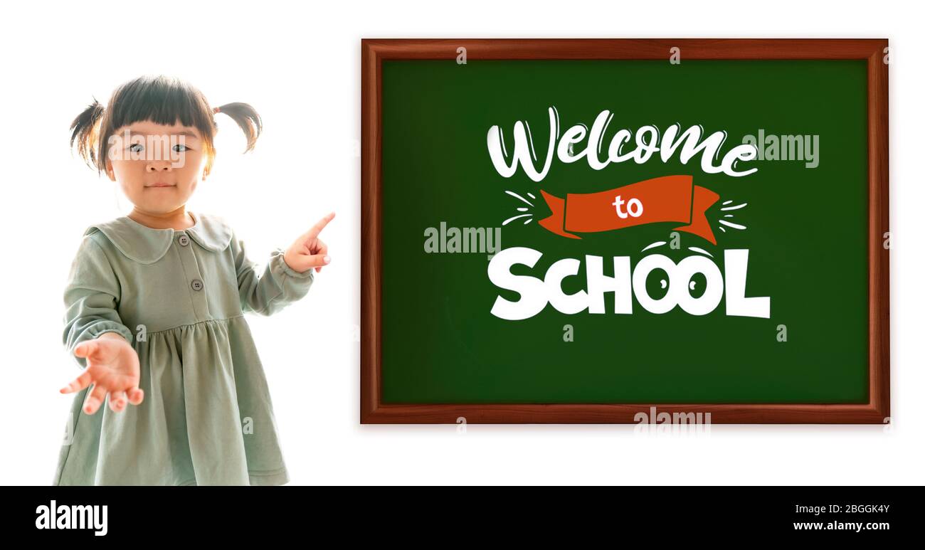 Bienvenido a la escuela. Feliz niña asiática apuntando con el dedo a la pizarra. Tiempo de escuela. Foto de stock