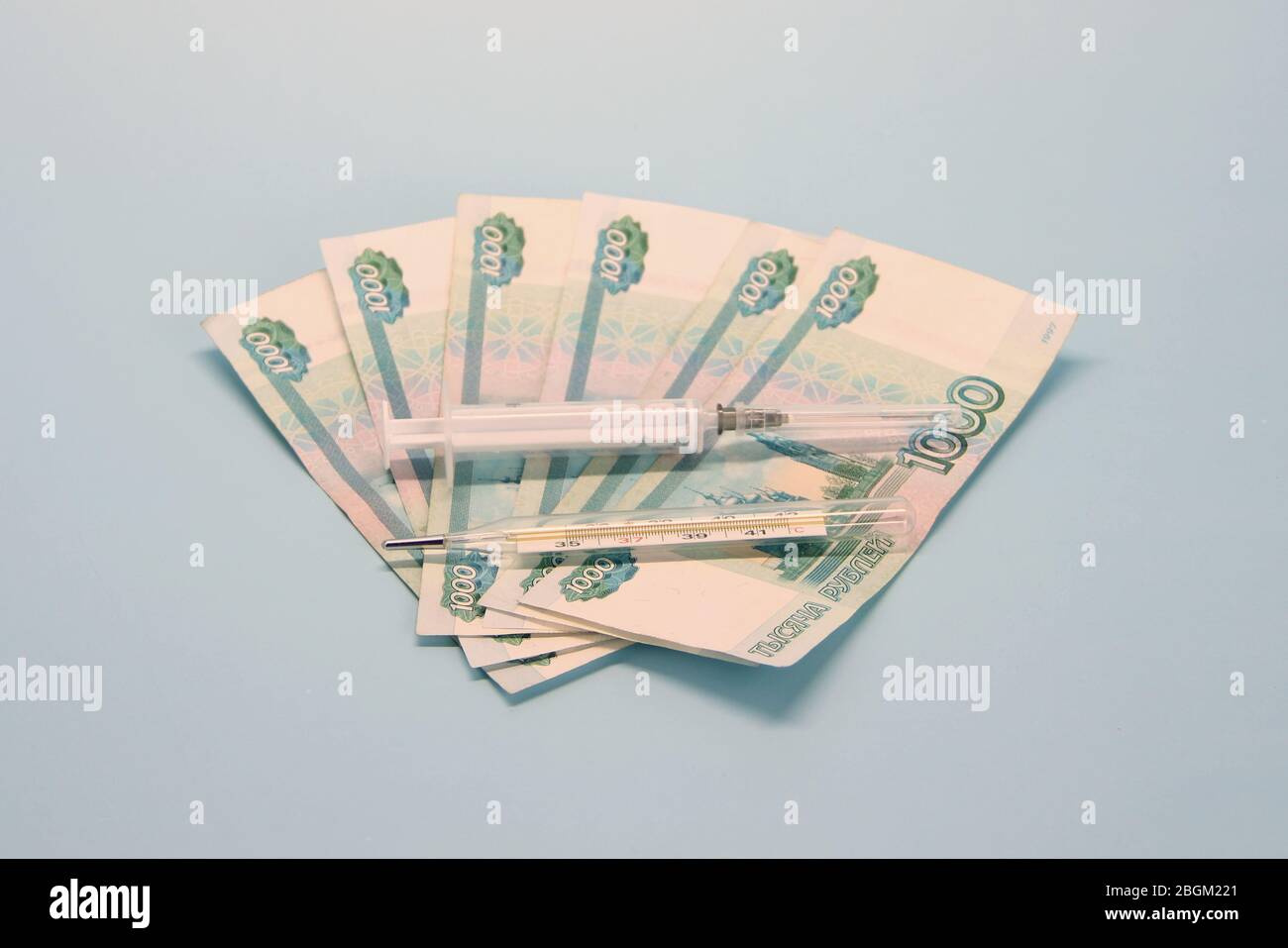 Billetes de papel moneda rusos de mil rublos denominados en un fan. La jeringa y el termómetro se encuentran en la parte superior. Foto de stock