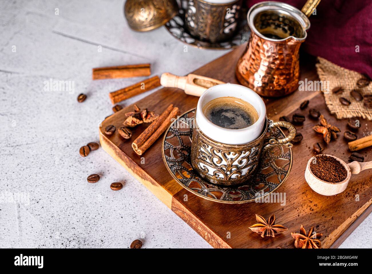 Taza de café, frijoles y cuchara con polvo molido sobre un fondo blanco moderno Foto de stock