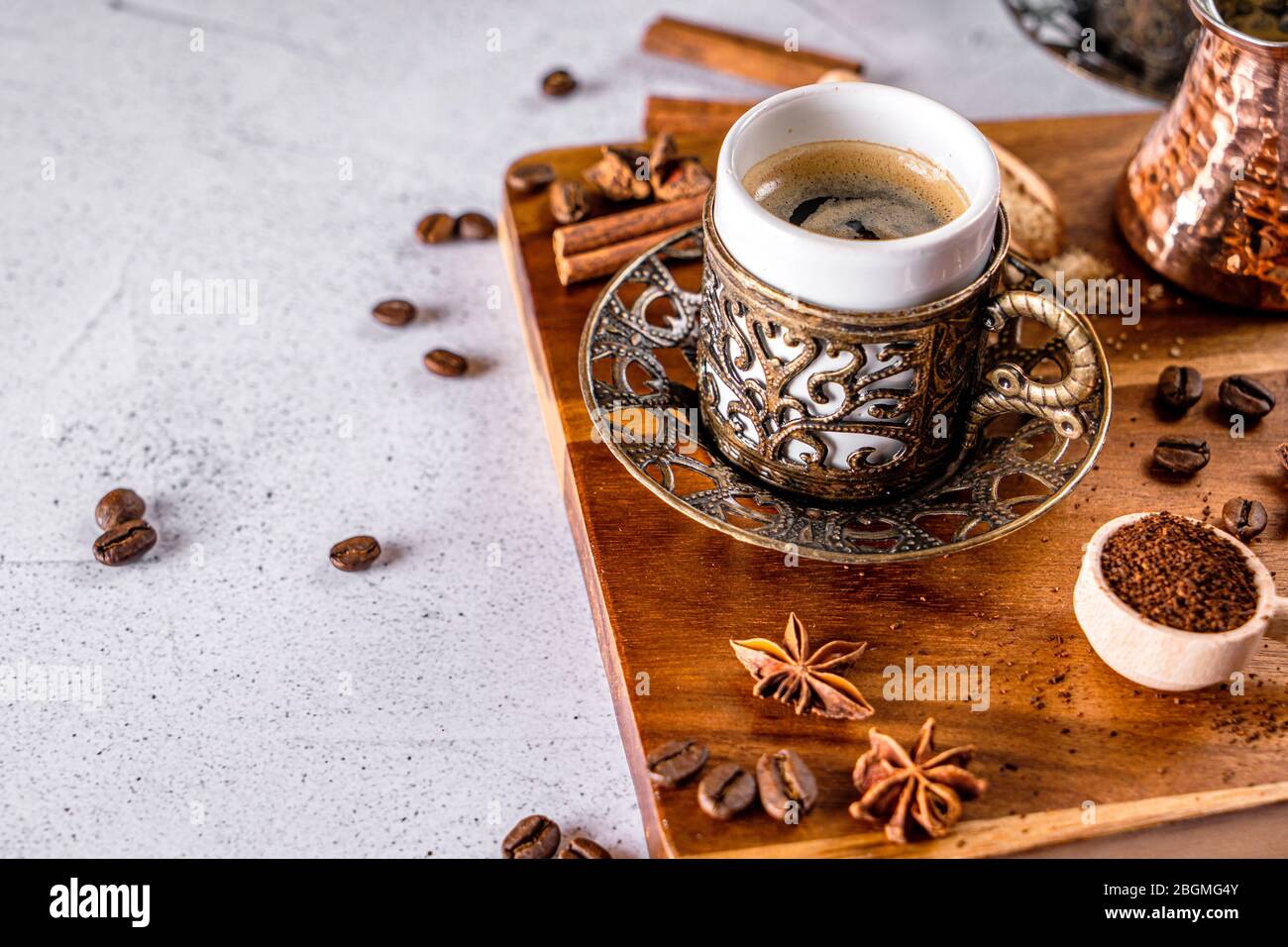 Café de estilo árabe oriental con granos de café y polvo sobre una mesa blanca Foto de stock