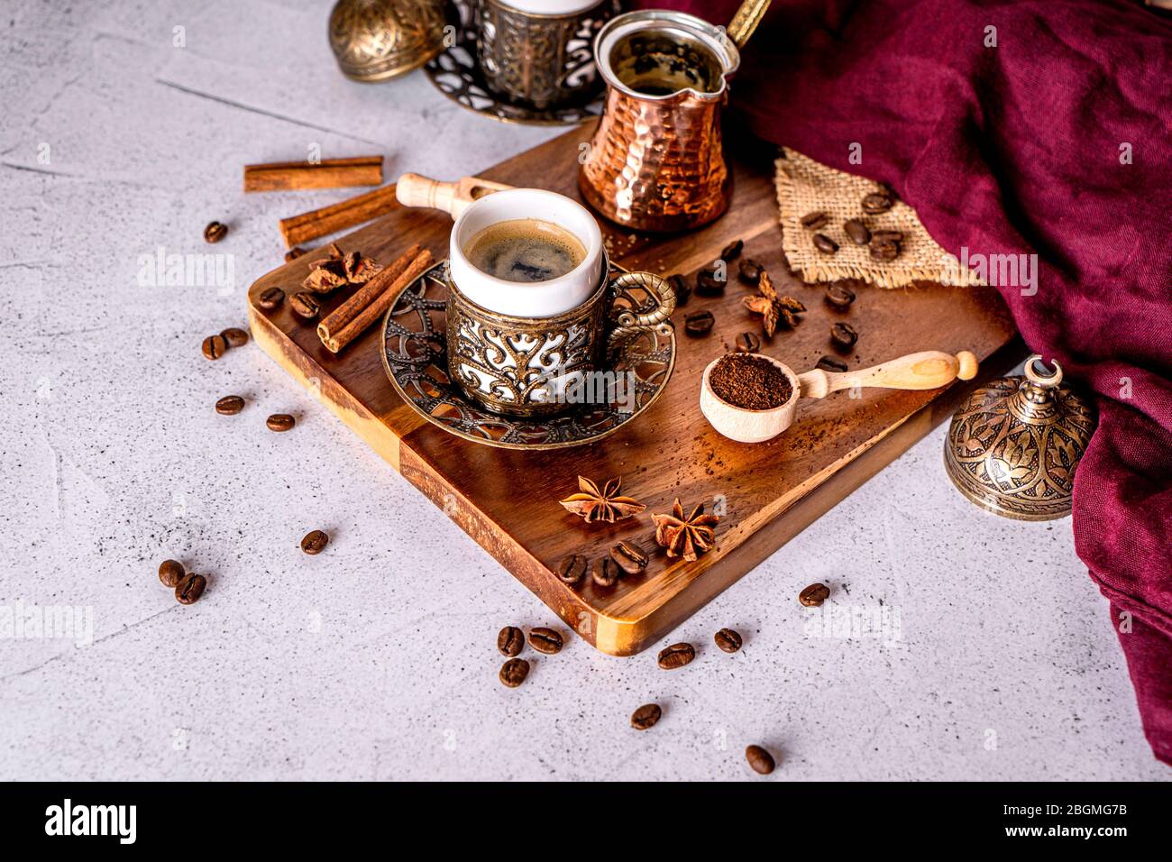 Detalle de una taza de café turca, granos de café y polvo molido sobre un fondo blanco con espacio para texto Foto de stock
