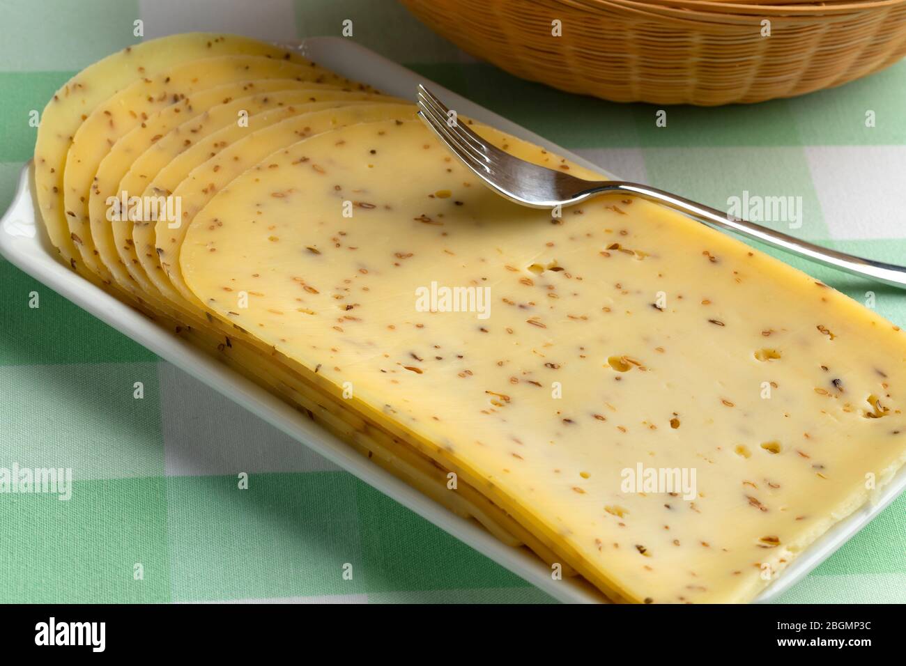Plato con queso tradicional de comino gouda cortado en rodajas Foto de stock