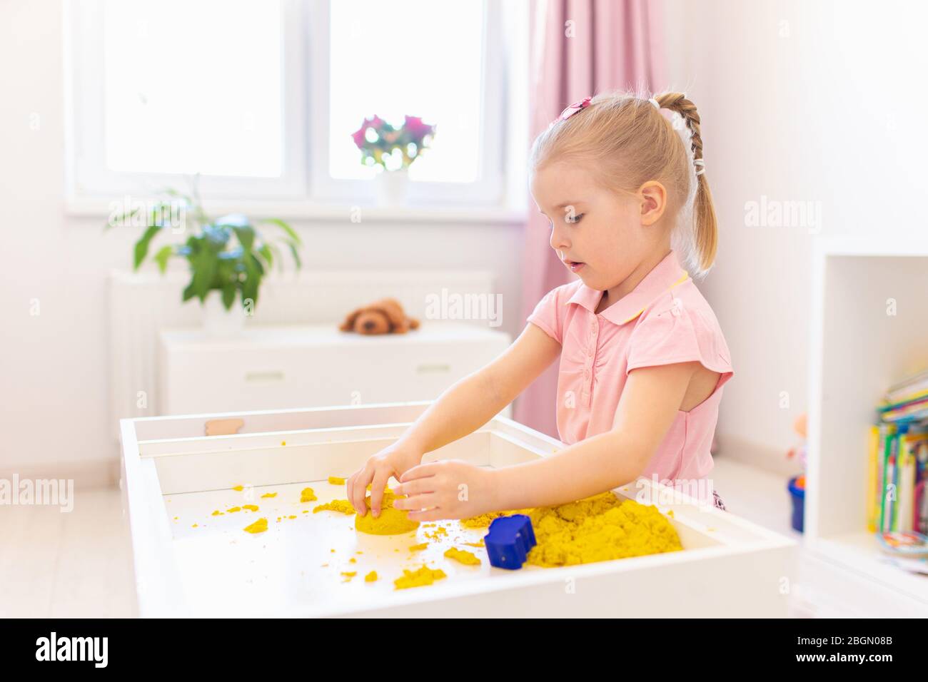 Niña rubia jugando con arena mágica amarilla en una mesa blanca en una  habitación luminosa. Desarrollo sensorial. Clases en un jardín de infantes  Fotografía de stock - Alamy