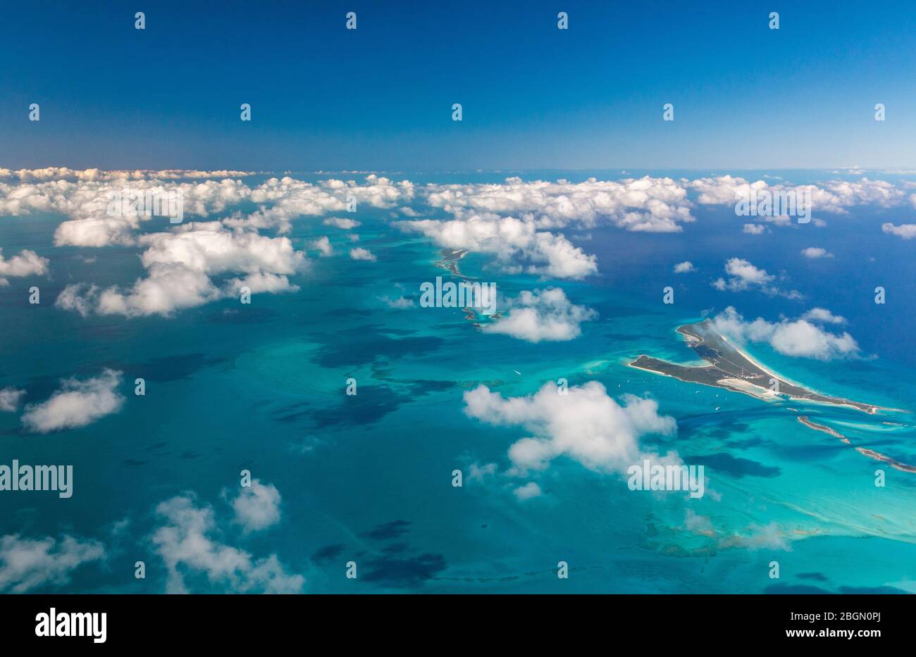 Vista aérea de las islas Bahama y las aguas azules circundantes, con pequeñas y suaves nubes blancas en las Bahamas Foto de stock