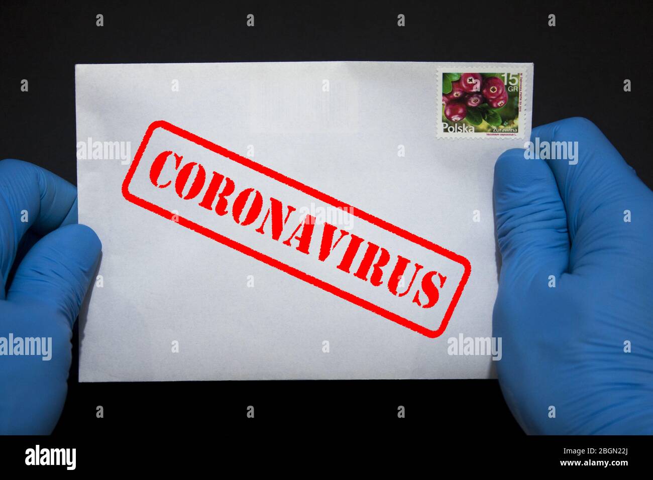 Manos humanas en guantes protectores con una carta que puede contener el virus COVID-19. Los artículos postales pueden propagar el Coronavirus. Foto de stock
