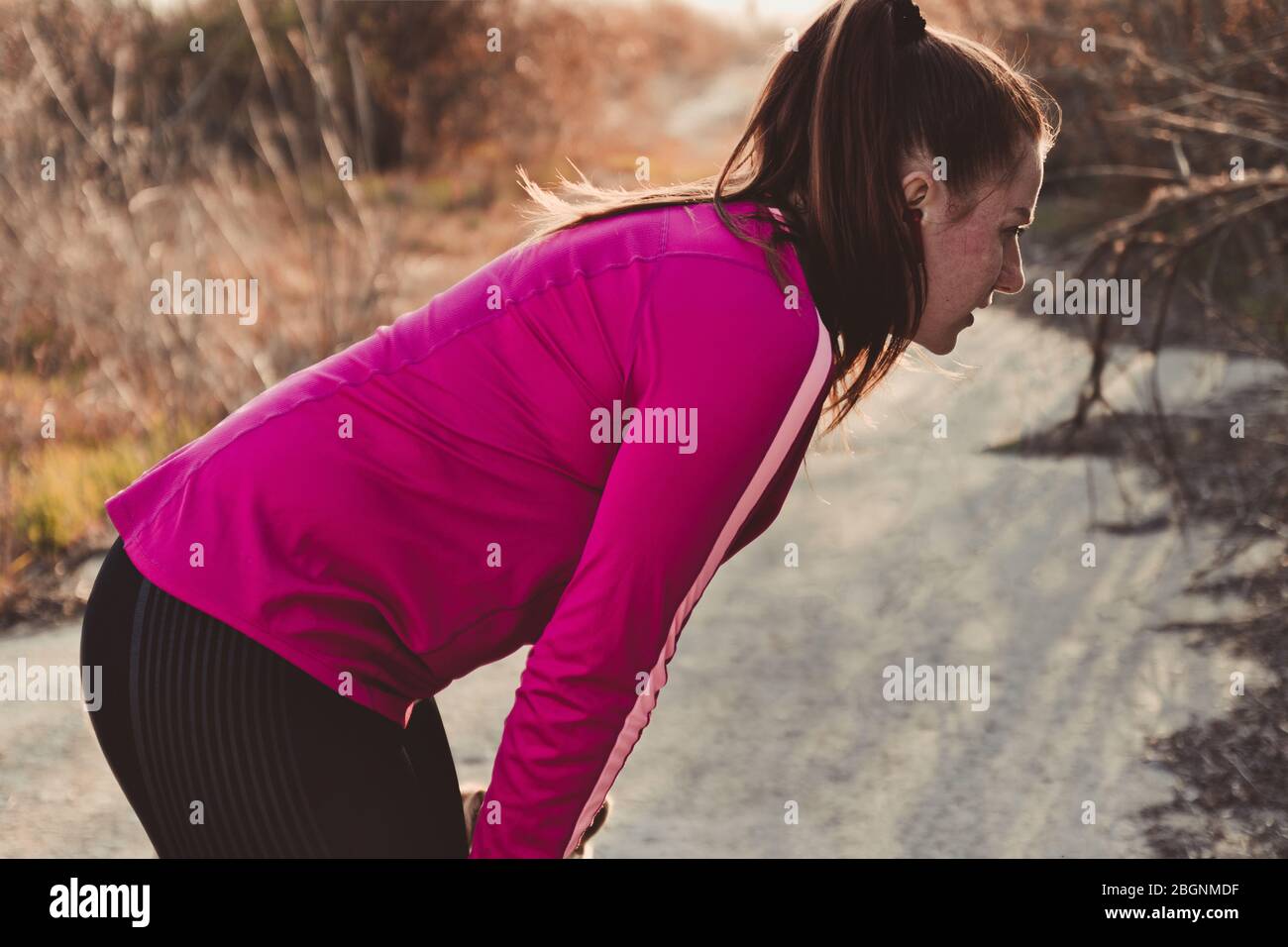 Una chica agotada de grasa corredor con una cara roja se siente mal después de correr o cardio de entrenamiento en la calle en un día soleado. Estilo de vida saludable Foto de stock