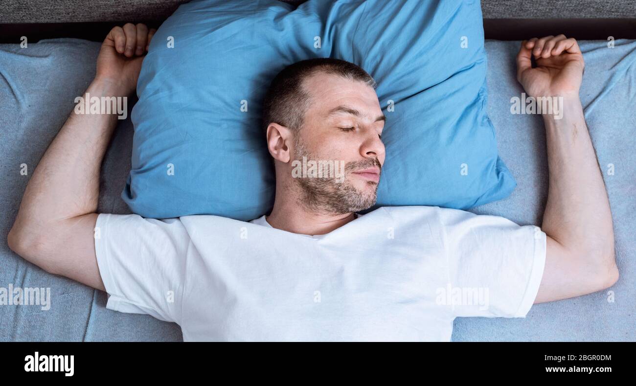 Hombre durmiendo y ronquidos Lying en la cama en el dormitorio, vista superior Foto de stock
