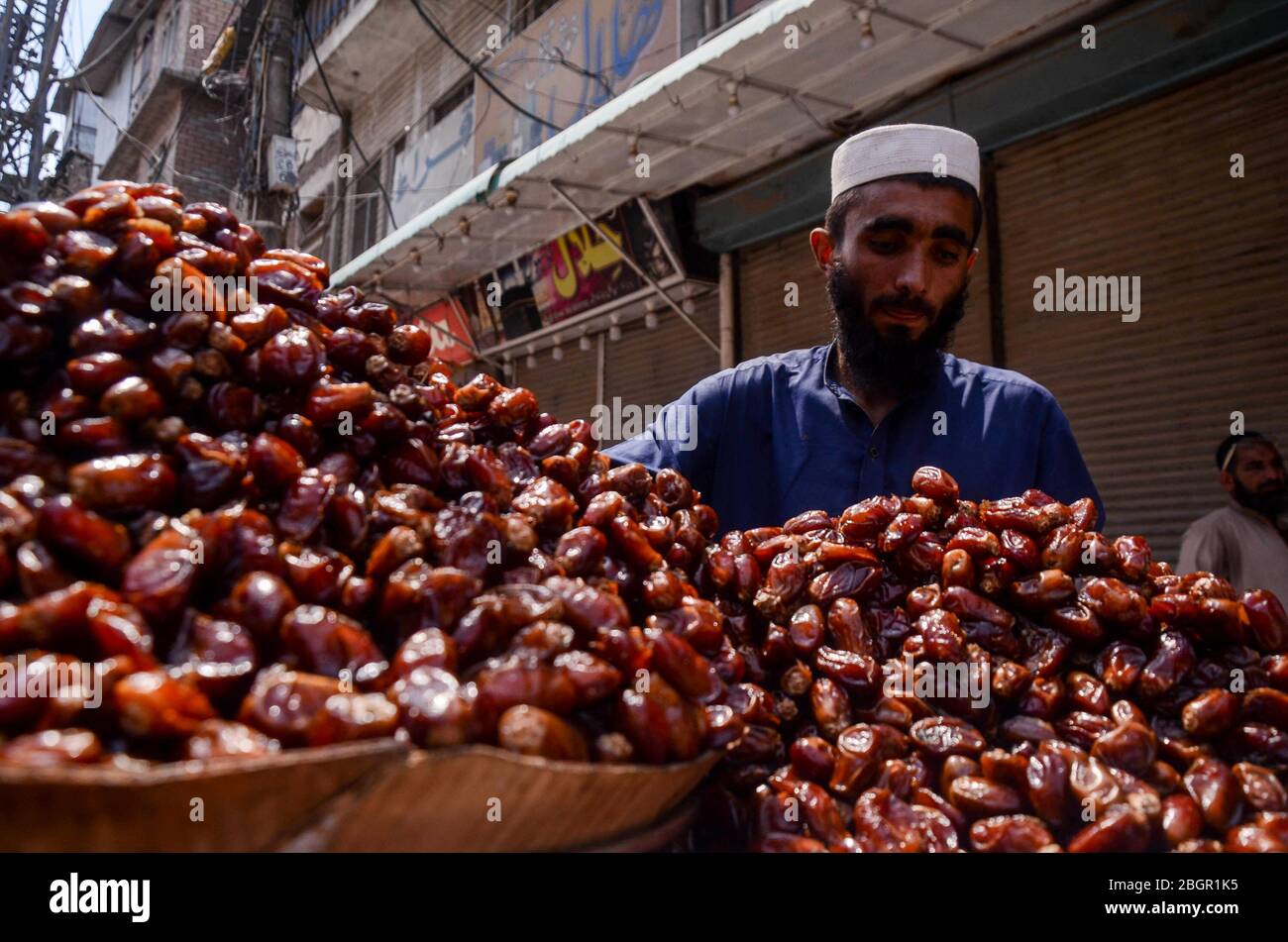 22 de abril de 2020: Peshawar, Pakistán. 22 de abril de 2020. La gente compra diferentes variedades de fechas a vendedores ambulantes en la calle del mercado Peepal Mandi en Peshawar en preparación para el Ramadán. Las fechas son muy populares durante el mes sagrado musulmán del Ramadán. La comida que rompe el ayuno diario durante el Ramadán se llama Iftar, y es costumbre en muchos países que los musulmanes rompan su ayuno en el momento de Iftar consumiendo fechas crédito: Hasnain Ali/IMAGESLIVE/ZUMA Wire/Alamy Live News Foto de stock
