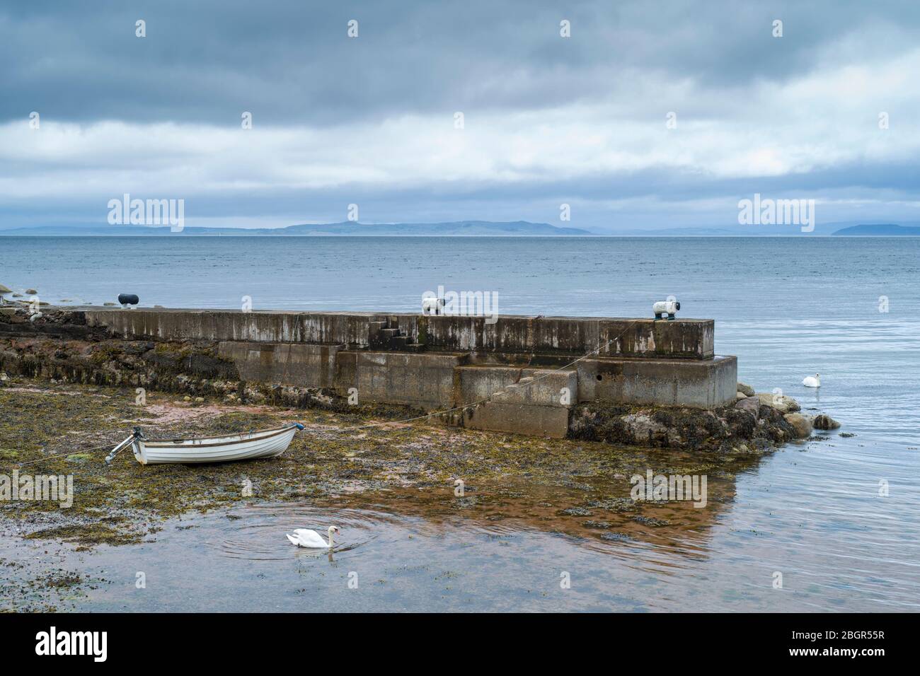 Barco de remo atado a un bolardo de ovejas y amarrado en la orilla del mar en el muelle cerca de Corrie en la Isla de Arran, Escocia Foto de stock