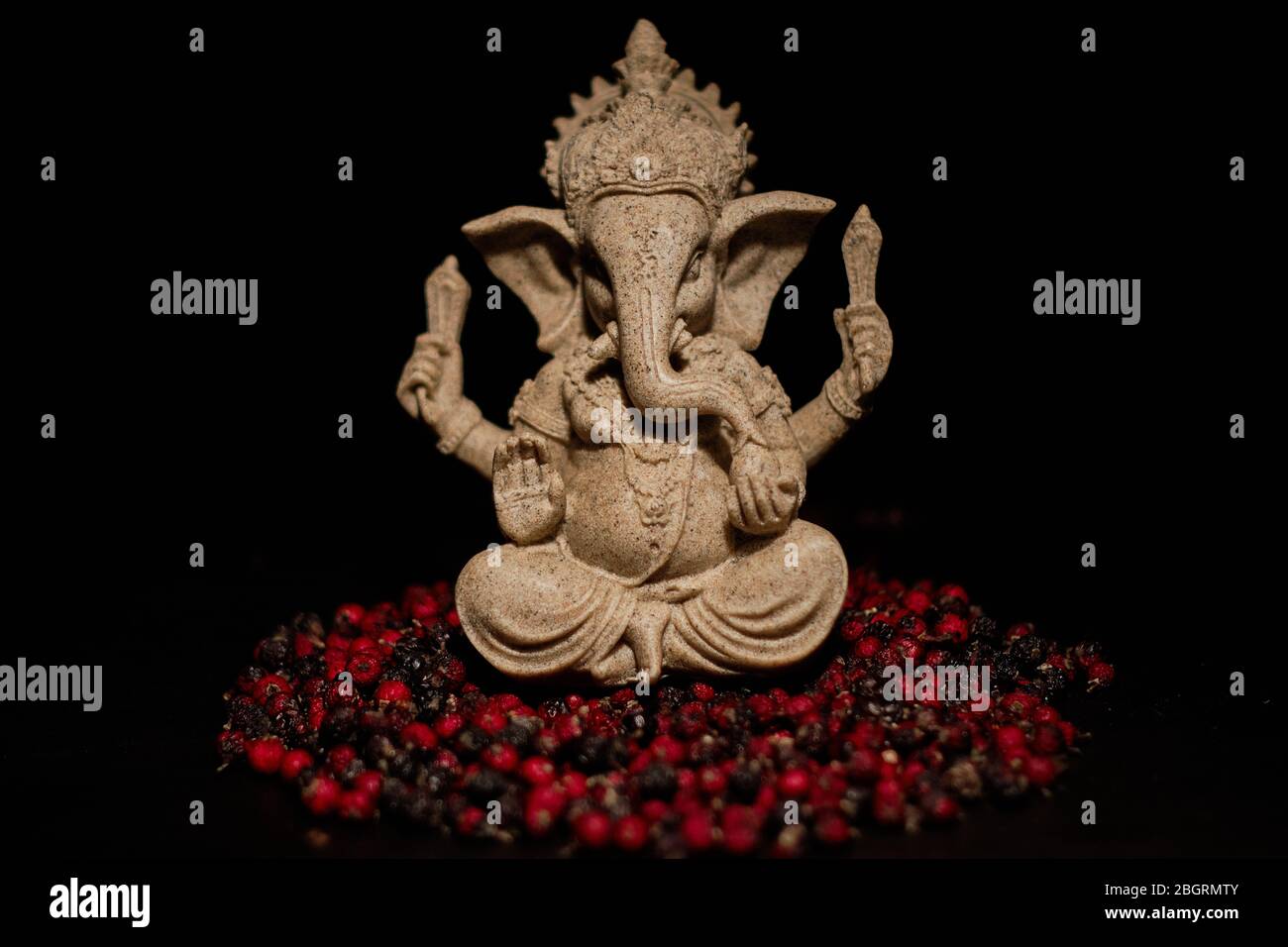 Imagen que representa a una deidad India, ganesha sentado en un puñado de semillas de acebo Foto de stock