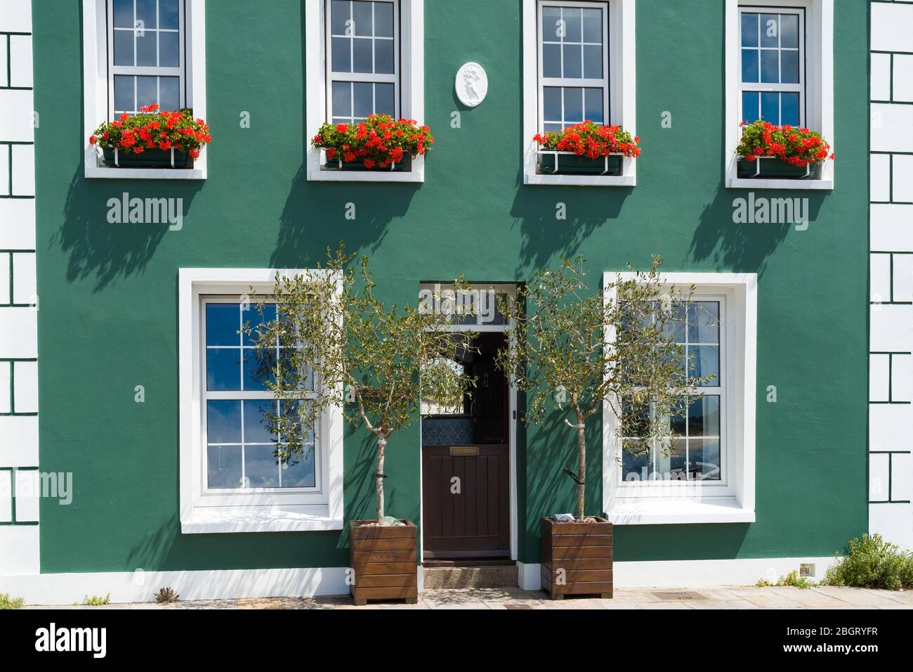 Elegante casa junto al puerto con par de olivos y geranios en cajas de ventanas frente al mar en Gorey, Jersey, Channel Iles Foto de stock