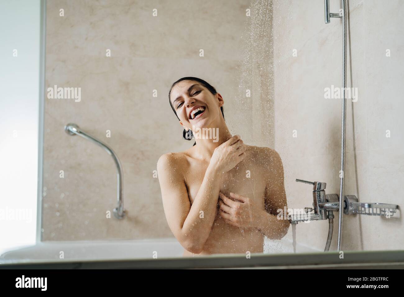 Feliz mujer disfrutando, teniendo una ducha fría rejuvenecedora, cantando.Baño higiene personal rutina.Cuidado personal.cuerpo, cabello, cuidado de la piel cosméticos.relajante casa Foto de stock