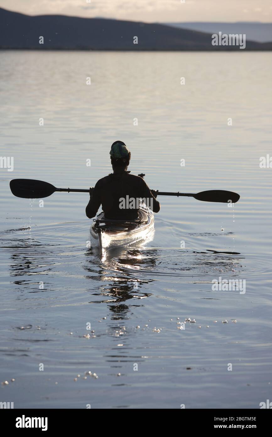 Hombre disfrutando de la serenidad del lago Myvatn en su kayak de mar Foto de stock